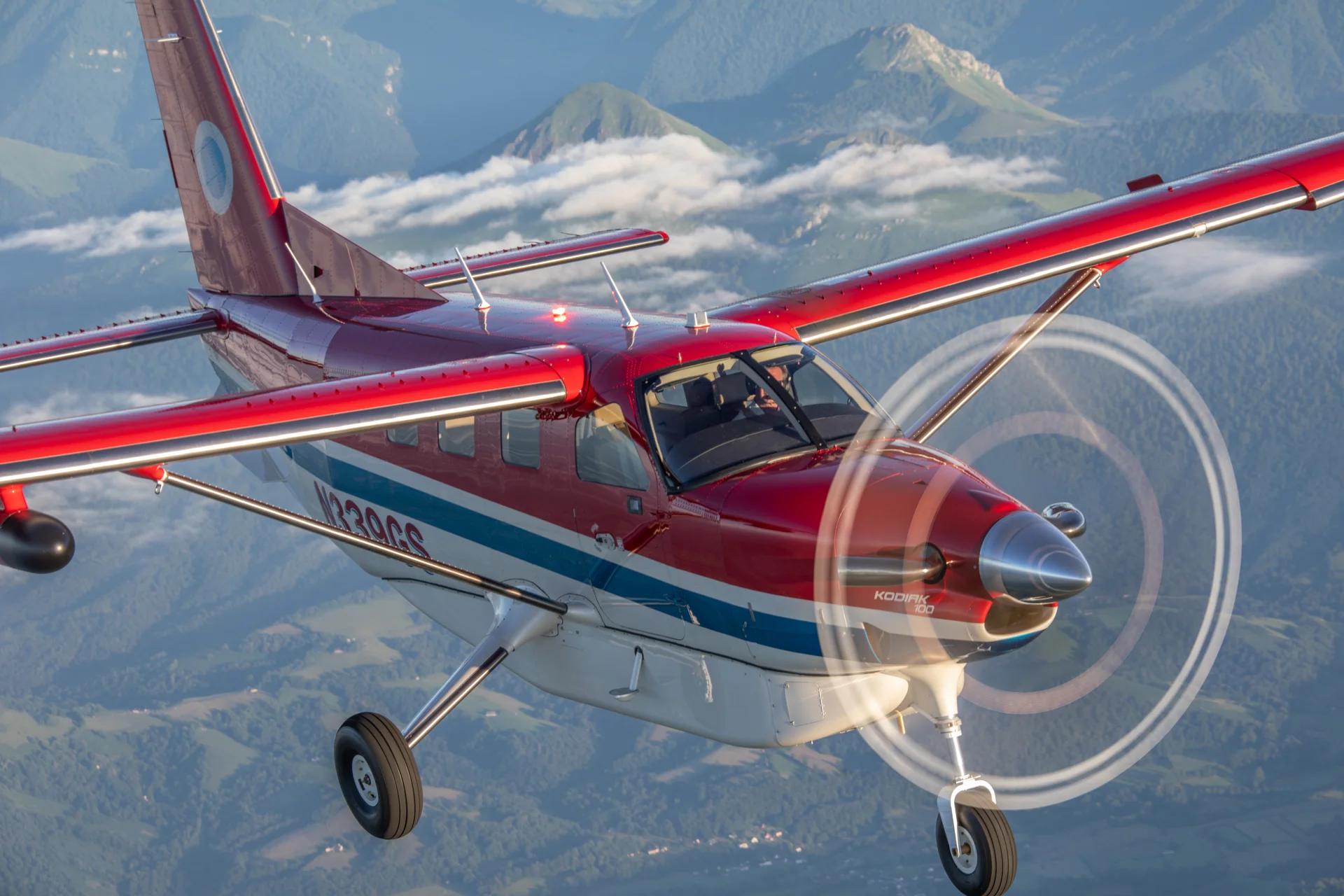 Daher Kodiak100 airborne over some hills and mountains
