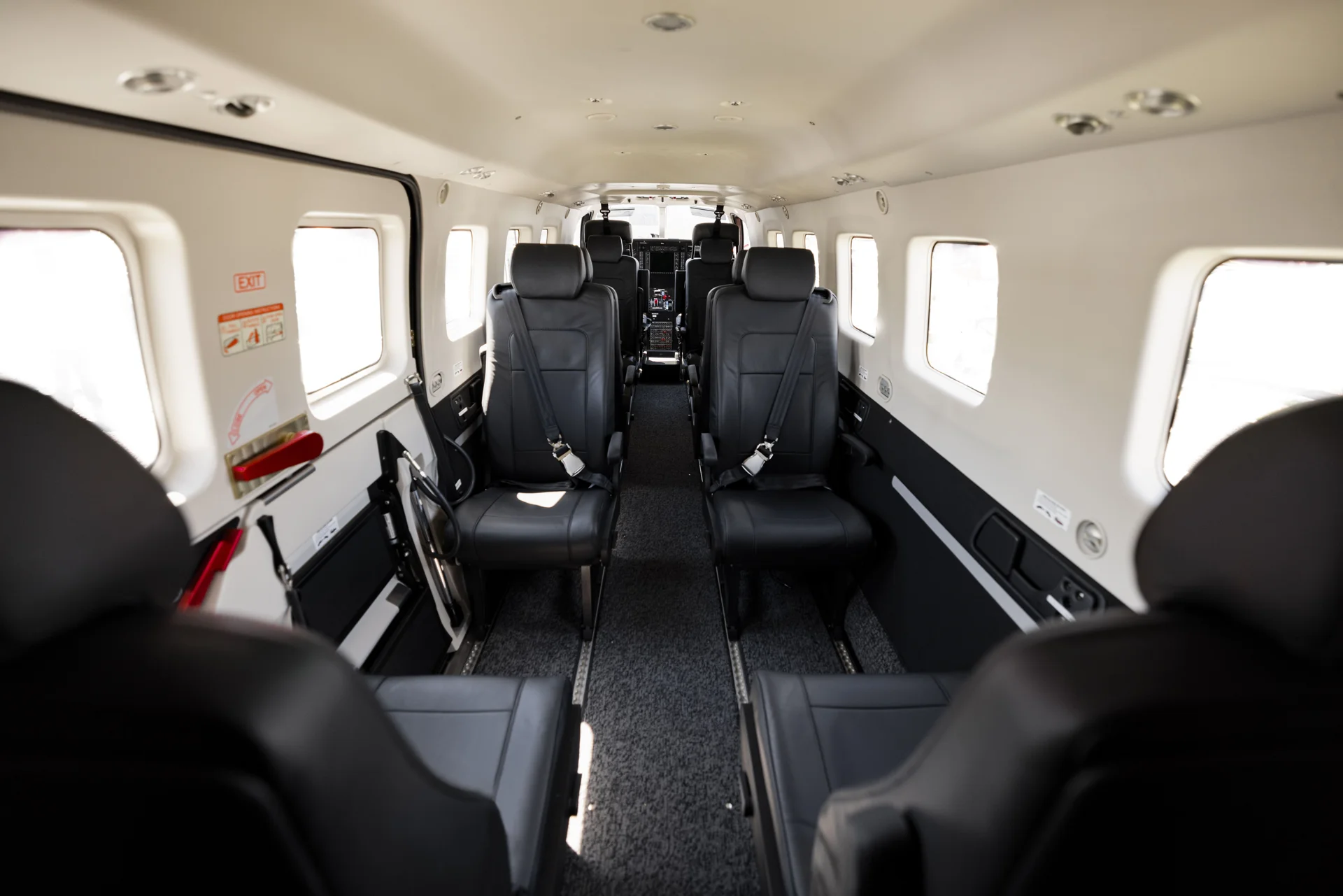 The spacious cabin of the Daher Kodiak 900. Beautiful dark leather seats and dark grey carpets. 