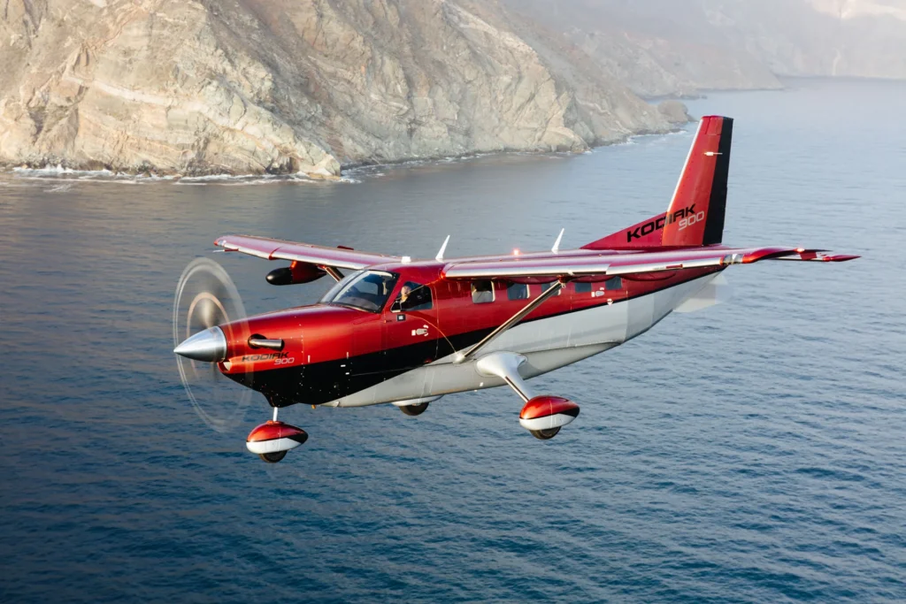 The Daher Kodiak 900 in flight over the water along the coast line