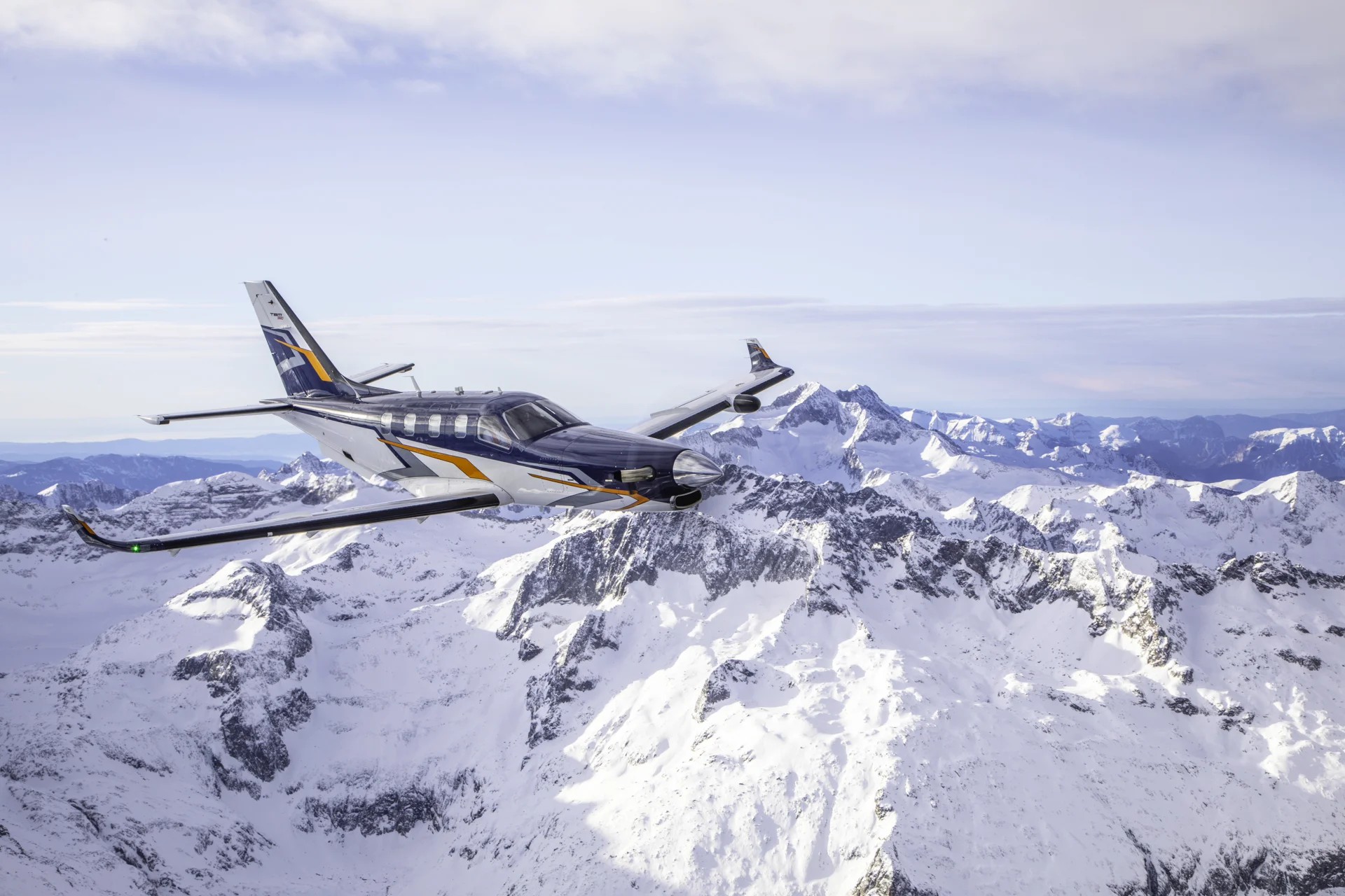 The Daher TBM 980 flying in snow clad mountainous terrain. 